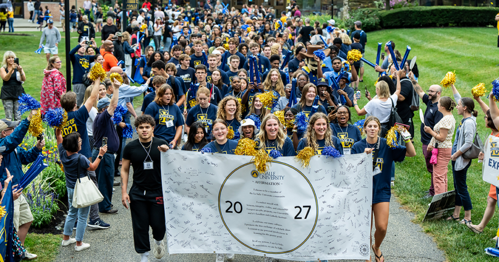 Image of students holding a Class of 2027 sign and walking to the Tom Gola Arena.