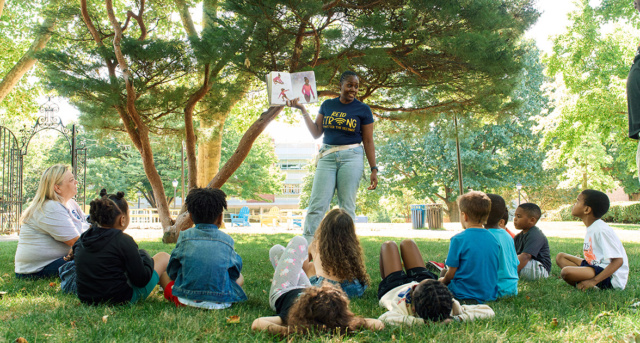 Photo of graduate student reading to summer camp students