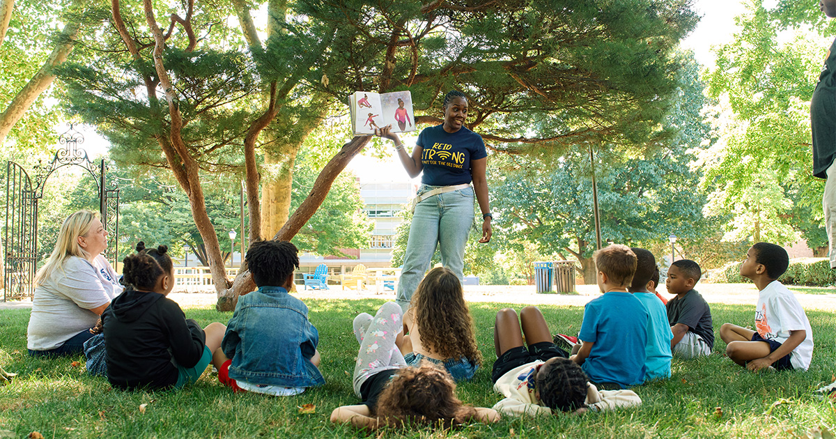 Photo of graduate student reading to summer camp students