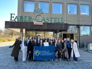 Image of a group of students posing with a La Salle University flag.