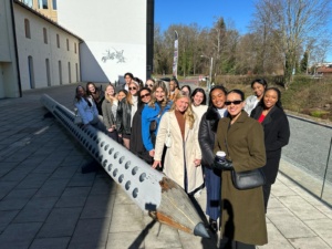 Image of students posing in front of a large sculpture of a pencil.